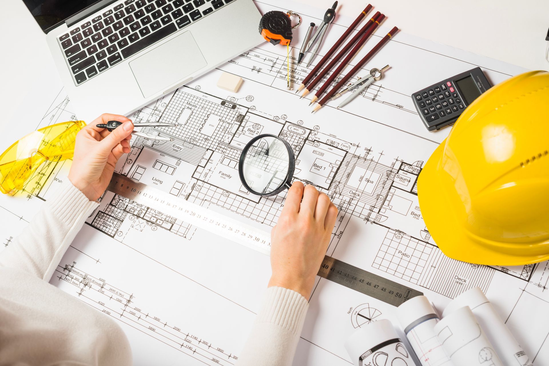 A person is looking at a blueprint with a magnifying glass.