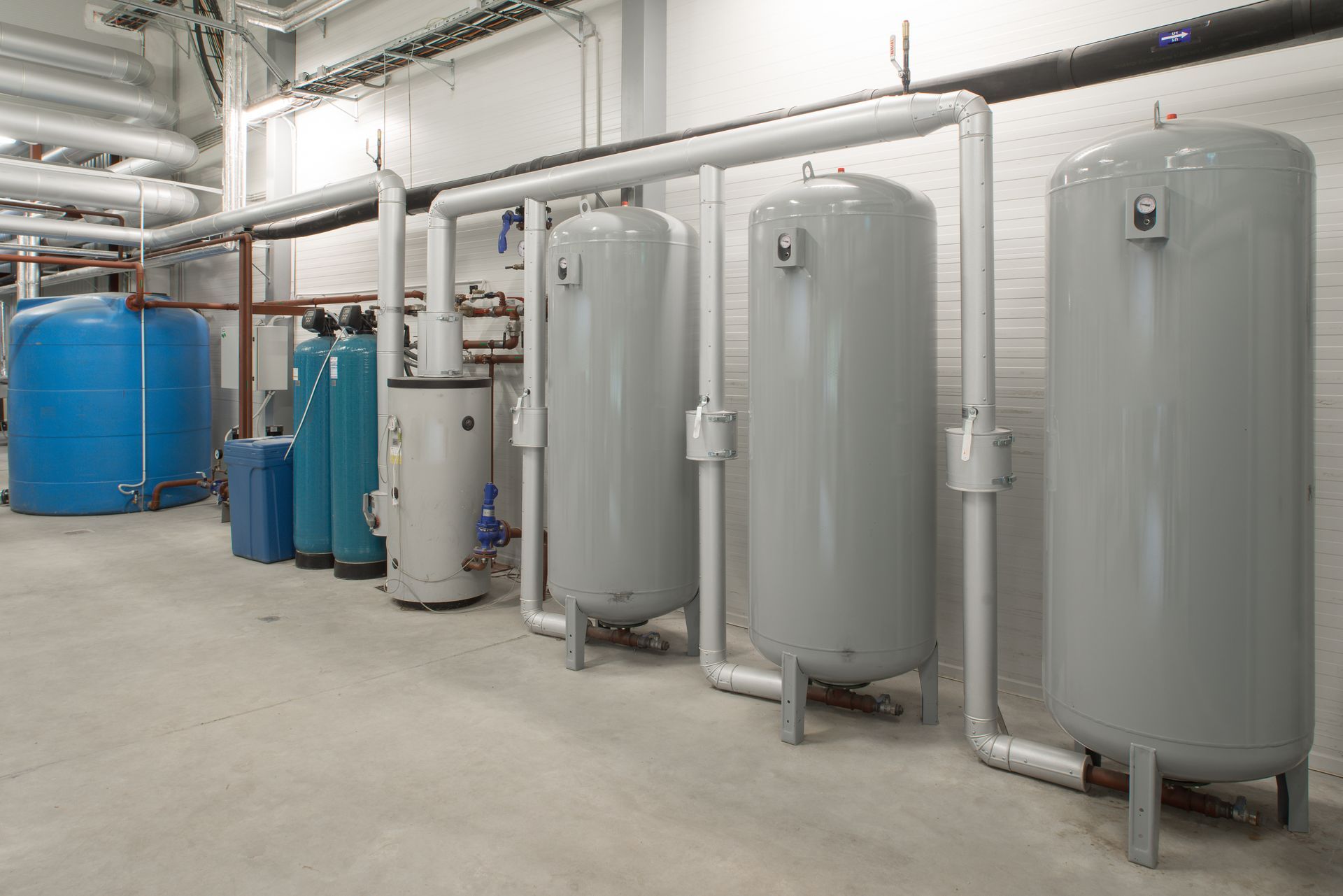 Large industrial tanks and connected piping system in a utility or boiler room. Large industrial tanks and connected piping system in a utility or boiler room.
