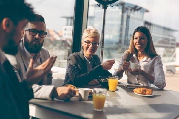 A group of people are sitting around a table drinking coffee and orange juice.