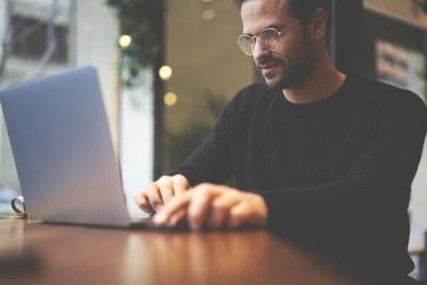 A man is sitting at a table using a laptop computer.