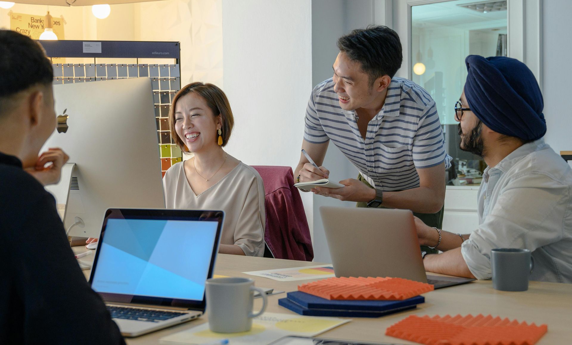 A group of people are sitting around a table with laptops.