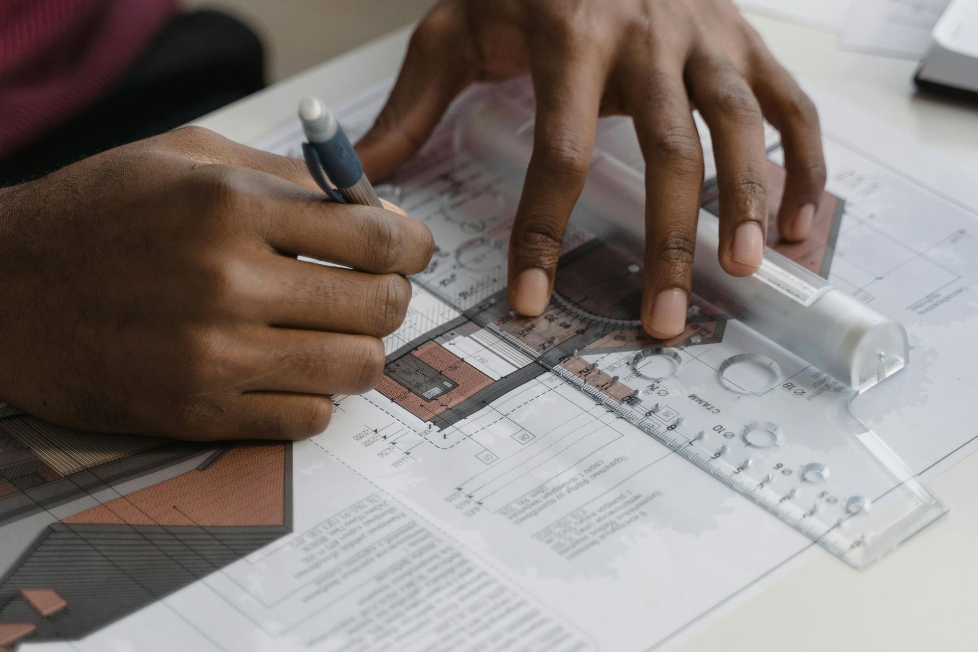 A person is using a ruler and a pen to draw on a piece of paper.