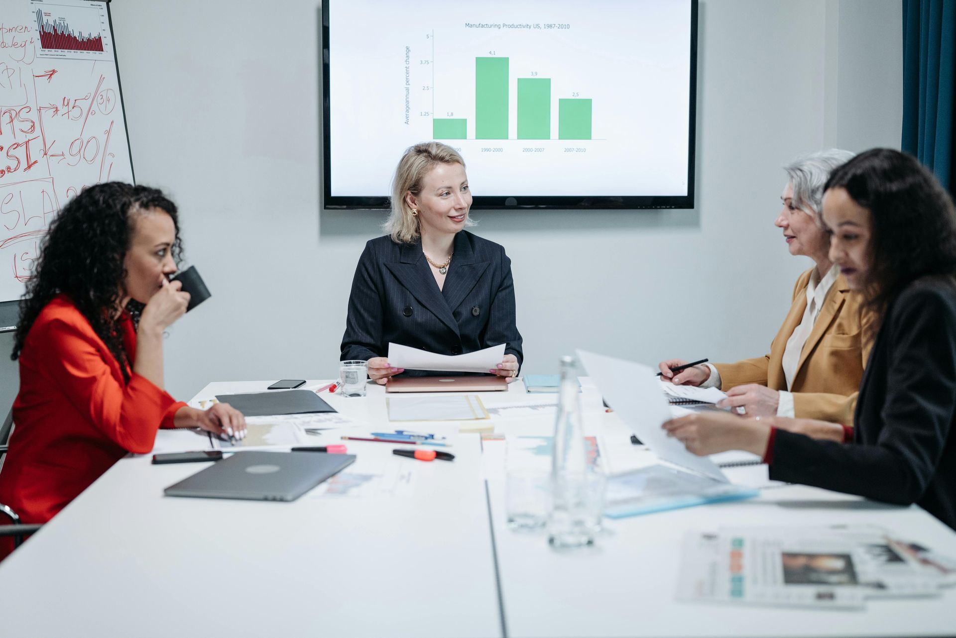 A group of women are sitting around a table in a conference room.