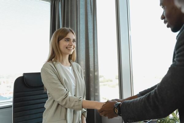A man and a woman are shaking hands in an office.