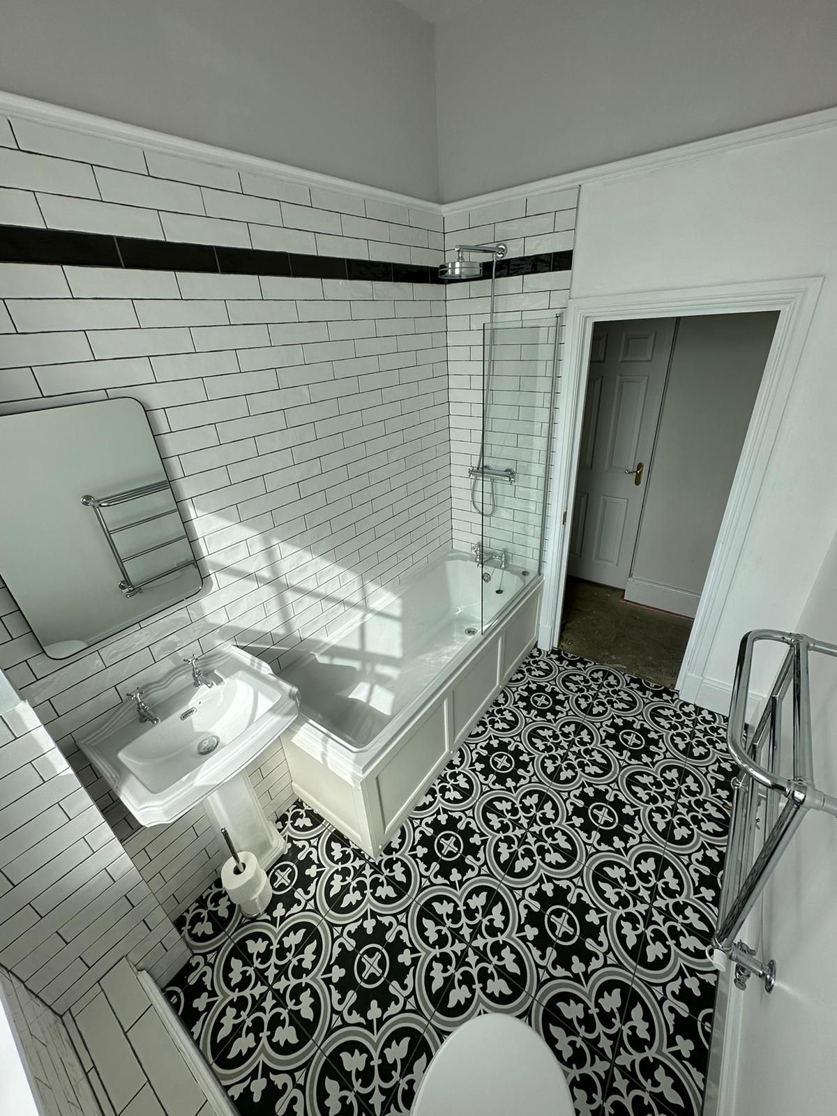 a bathroom with a bathtub , sink , mirror and towel rack .