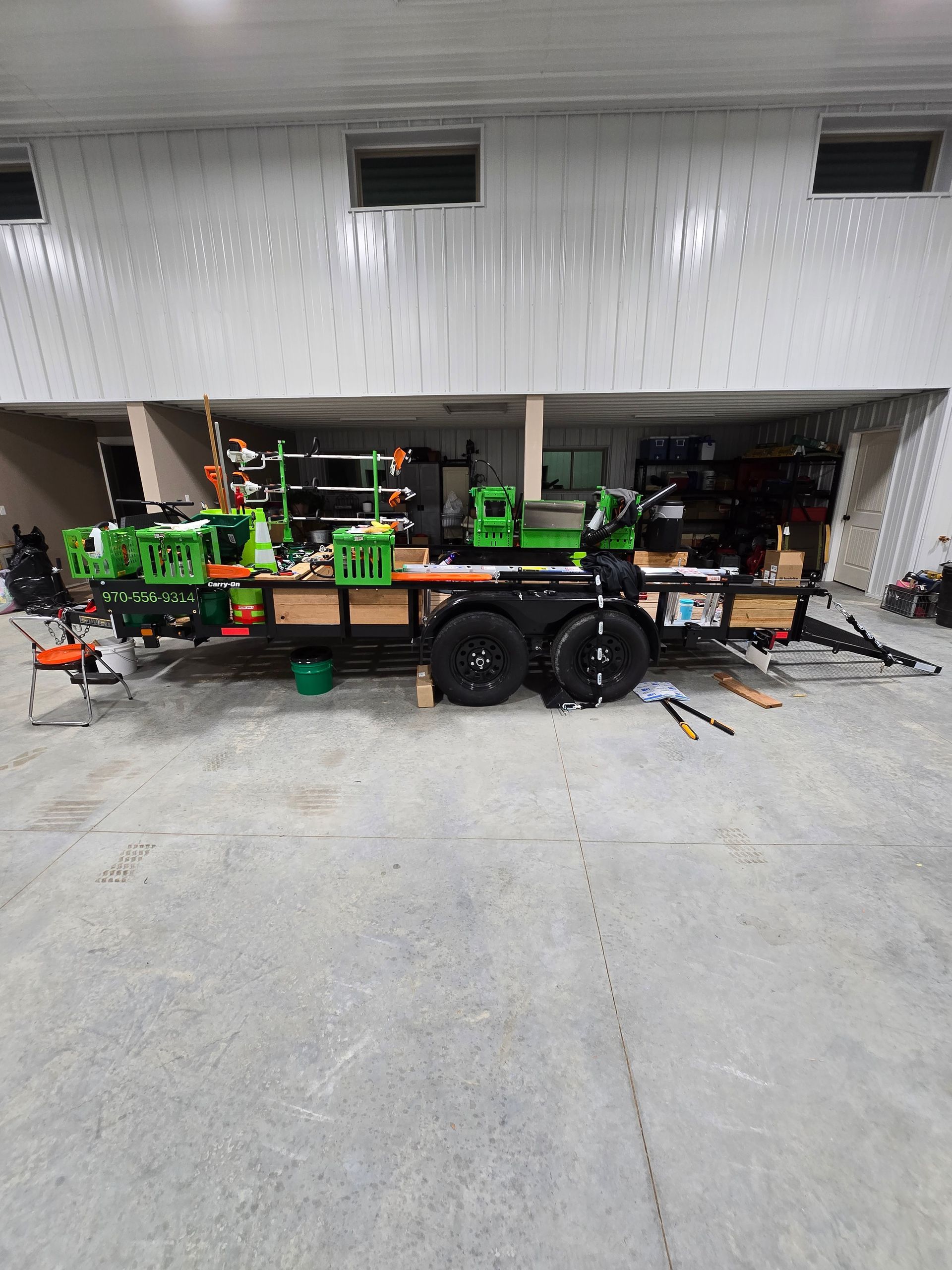 Green construction machinery on a trailer in a warehouse garage.