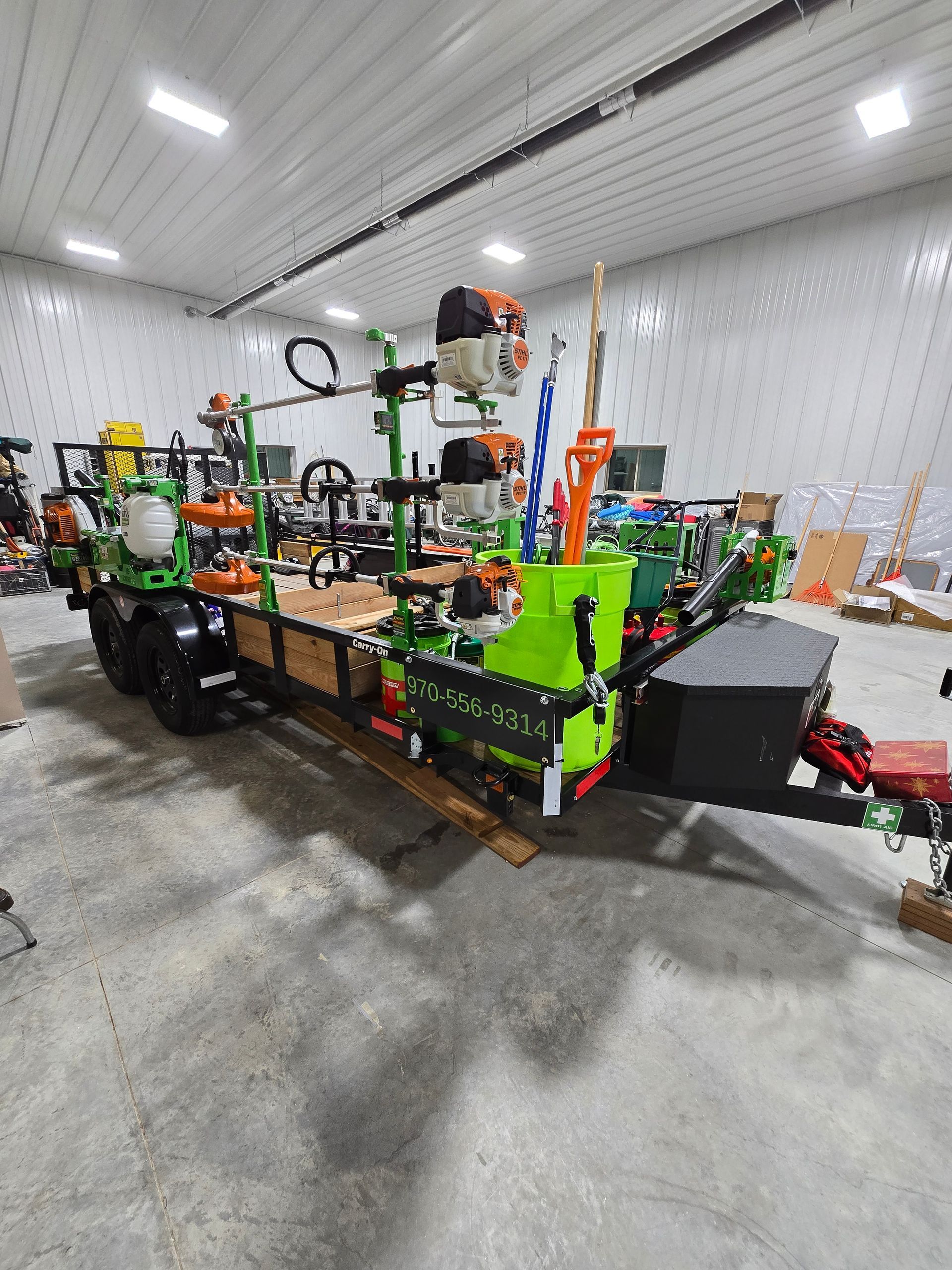Bright green and orange industrial machine in a garage-like workshop with concrete floor and white walls