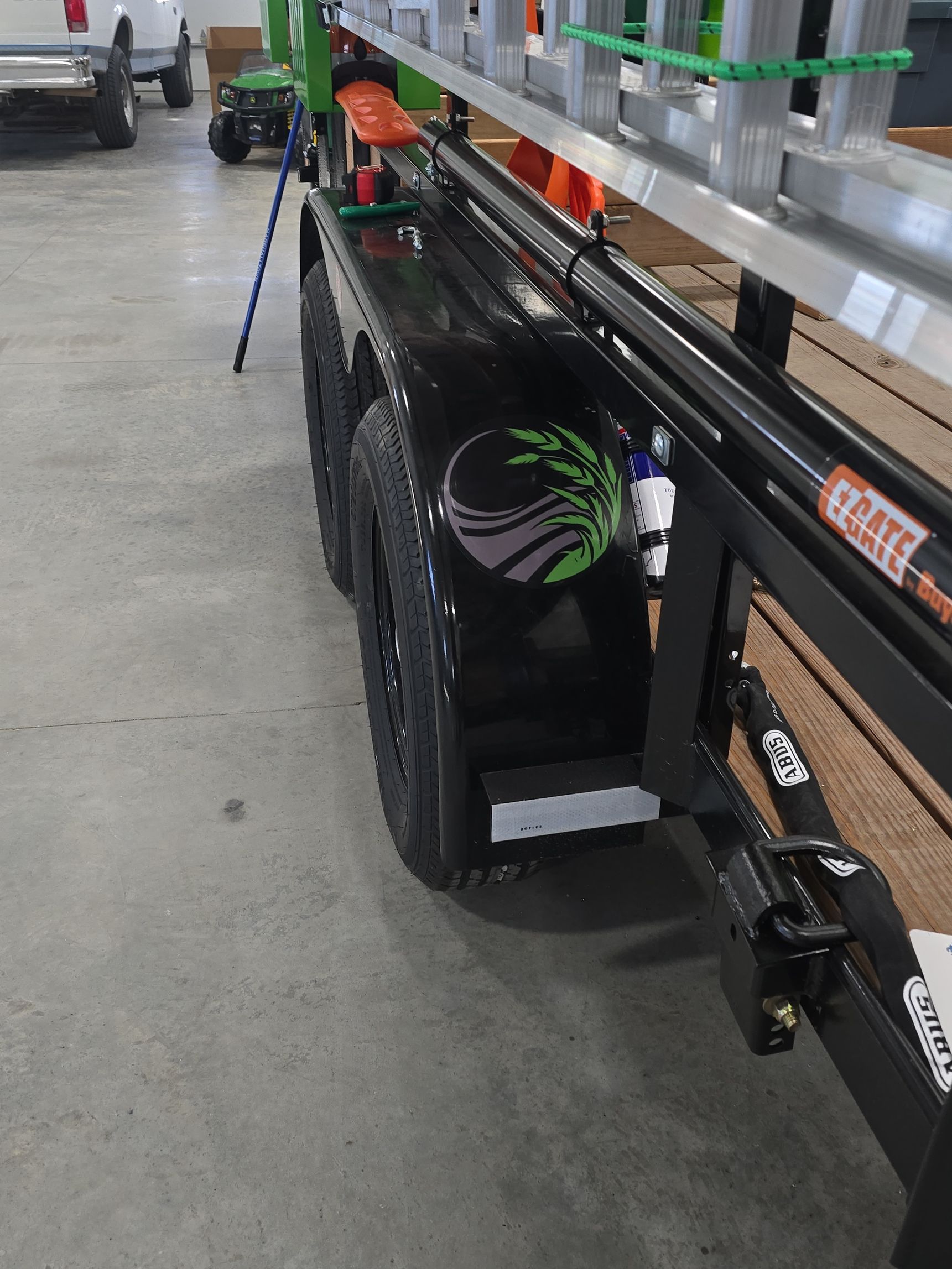 Black trailer with purple/green spiral fan graphics parked in a warehouse aisle, loaded with boxes.