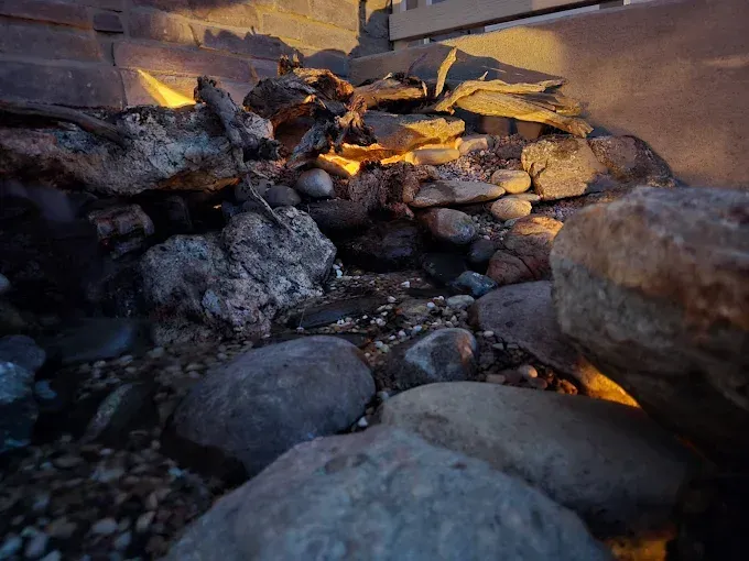 Rocky fire pit with glowing embers and flames between large stones at dusk