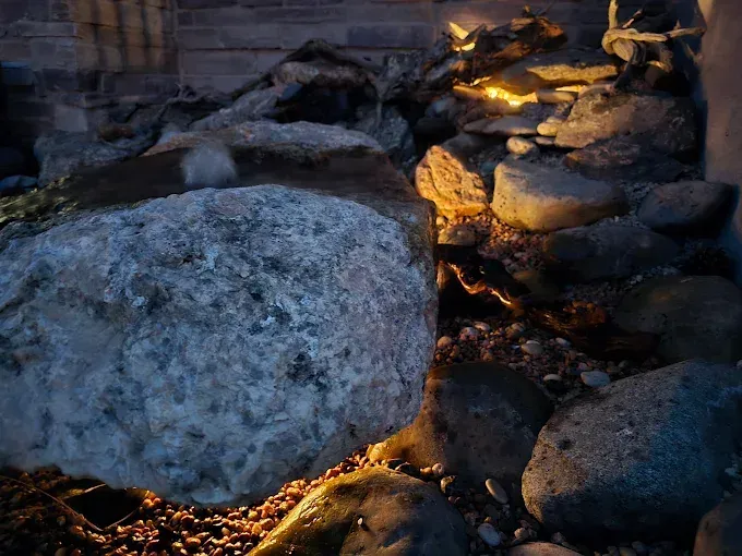 Large boulders lit by warm firelight in a rocky outdoor scene at dusk