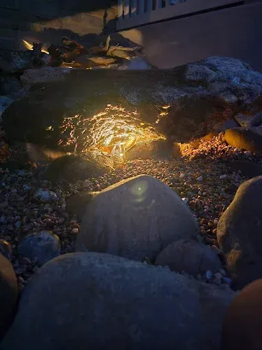 Snow-covered stones around a glowing lit fire pit at dusk