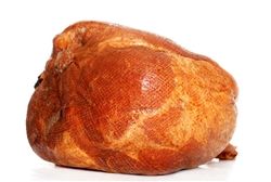 A large piece of ham is sitting on a white surface.