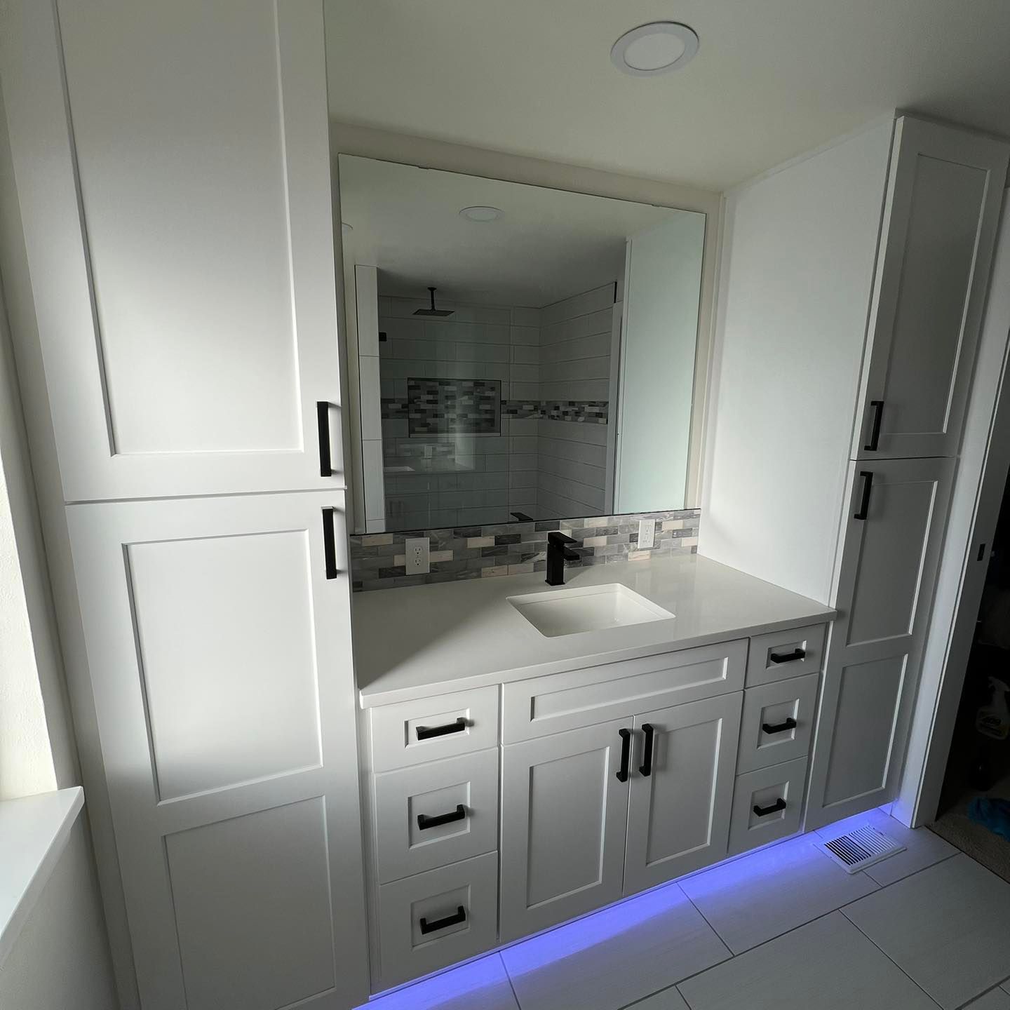 A bathroom with white cabinets , a sink and a mirror