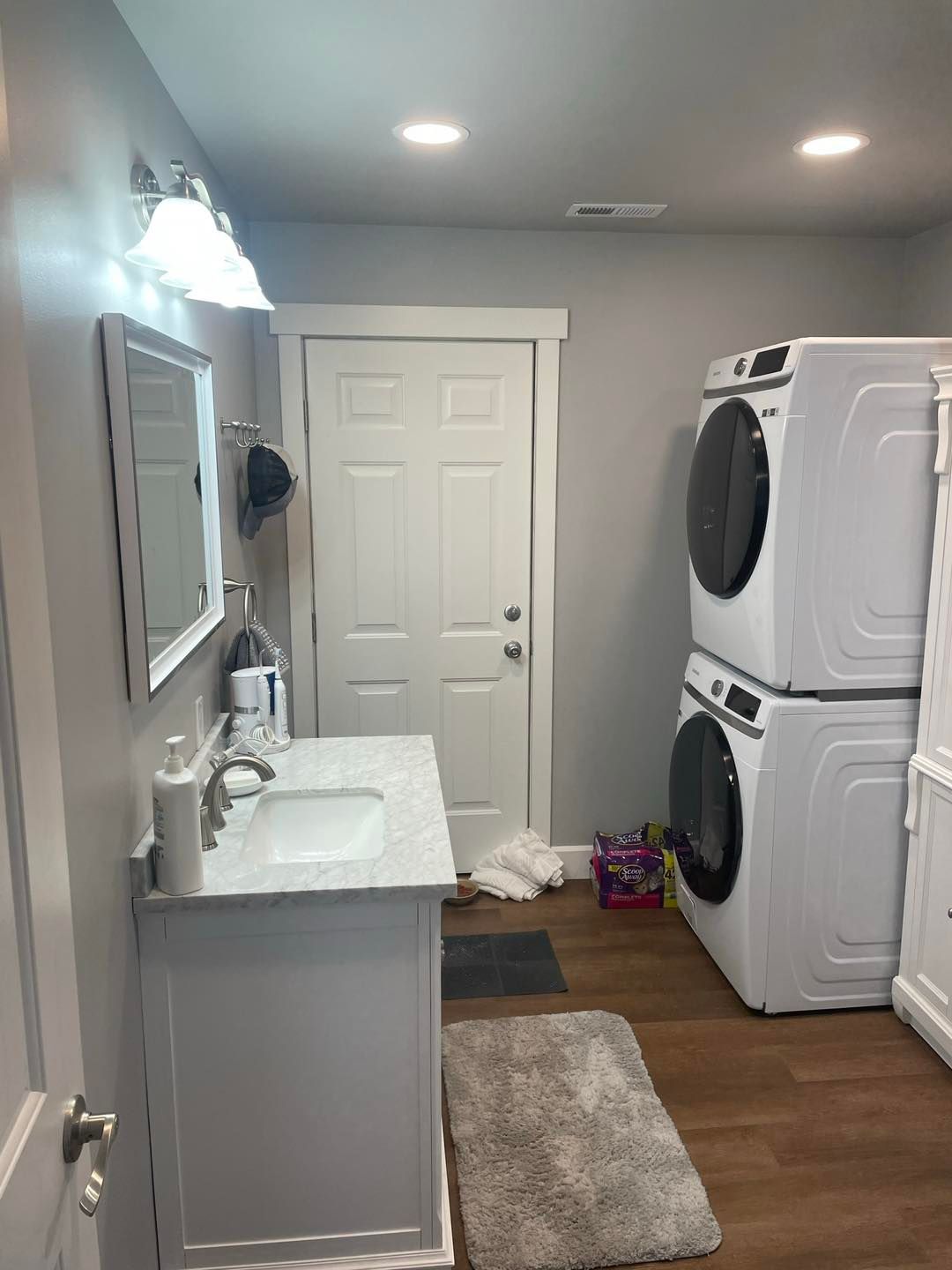 A bathroom with a sink , washer and dryer stacked on top of each other.