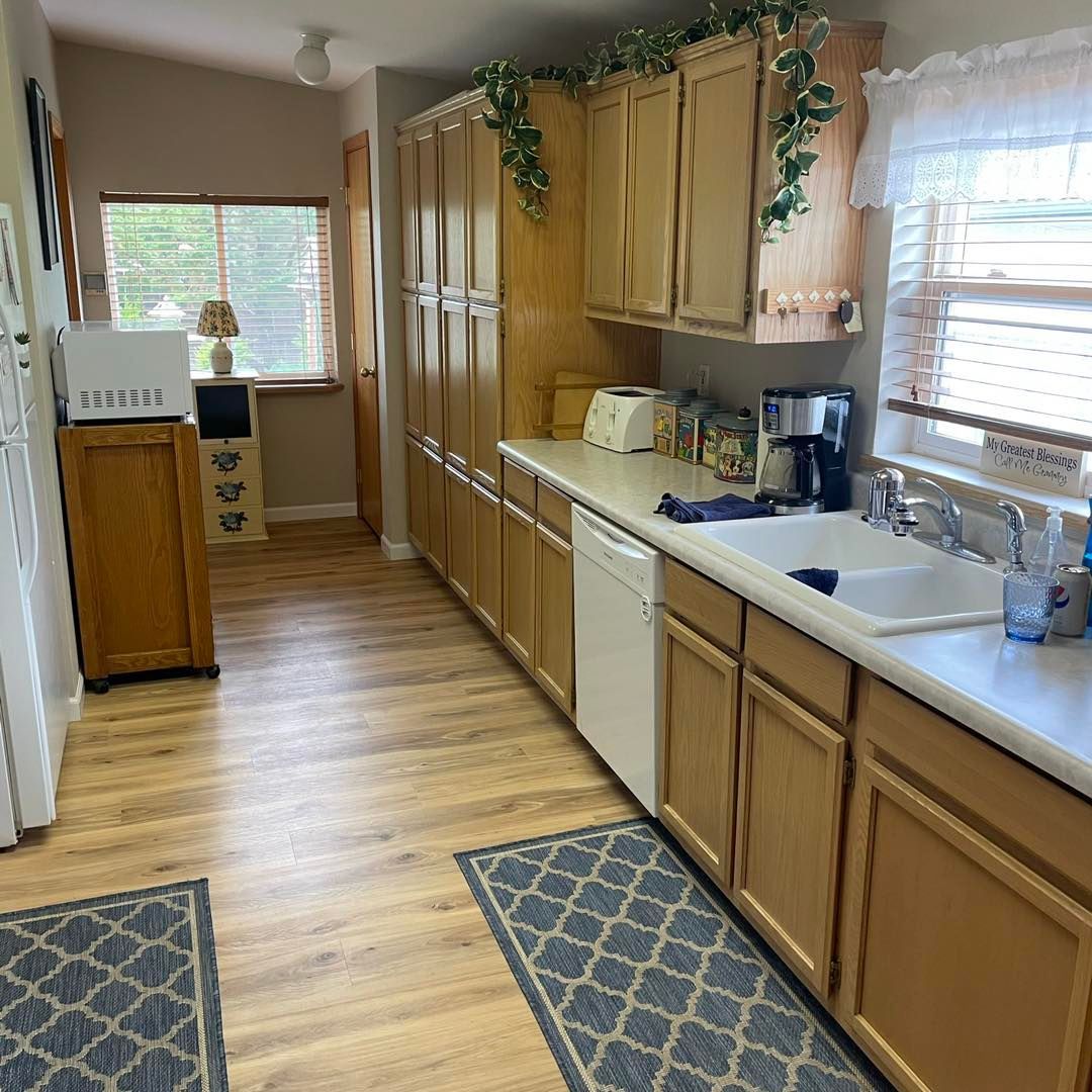 A kitchen with wooden cabinets , a sink , and a microwave