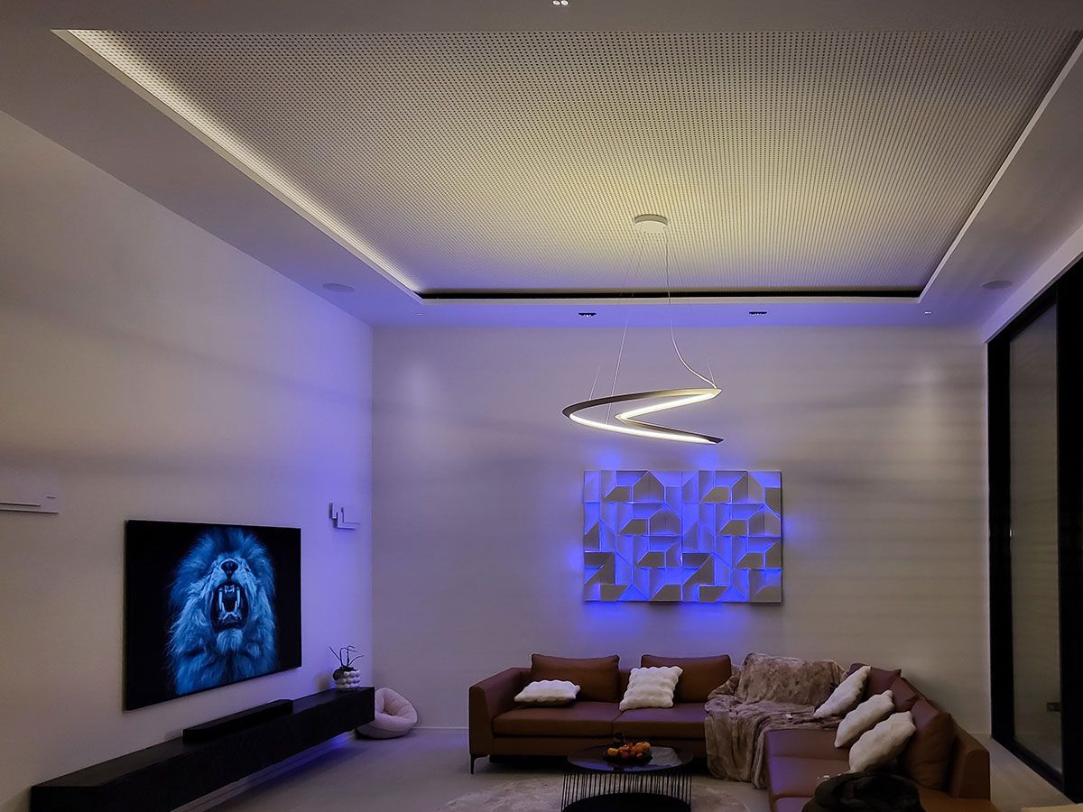 Modernes Wohnzimmer mit indirekter blauer RGB-Beleuchtung an der Wandkunst und einer geschwungenen LED-Pendelleuchte