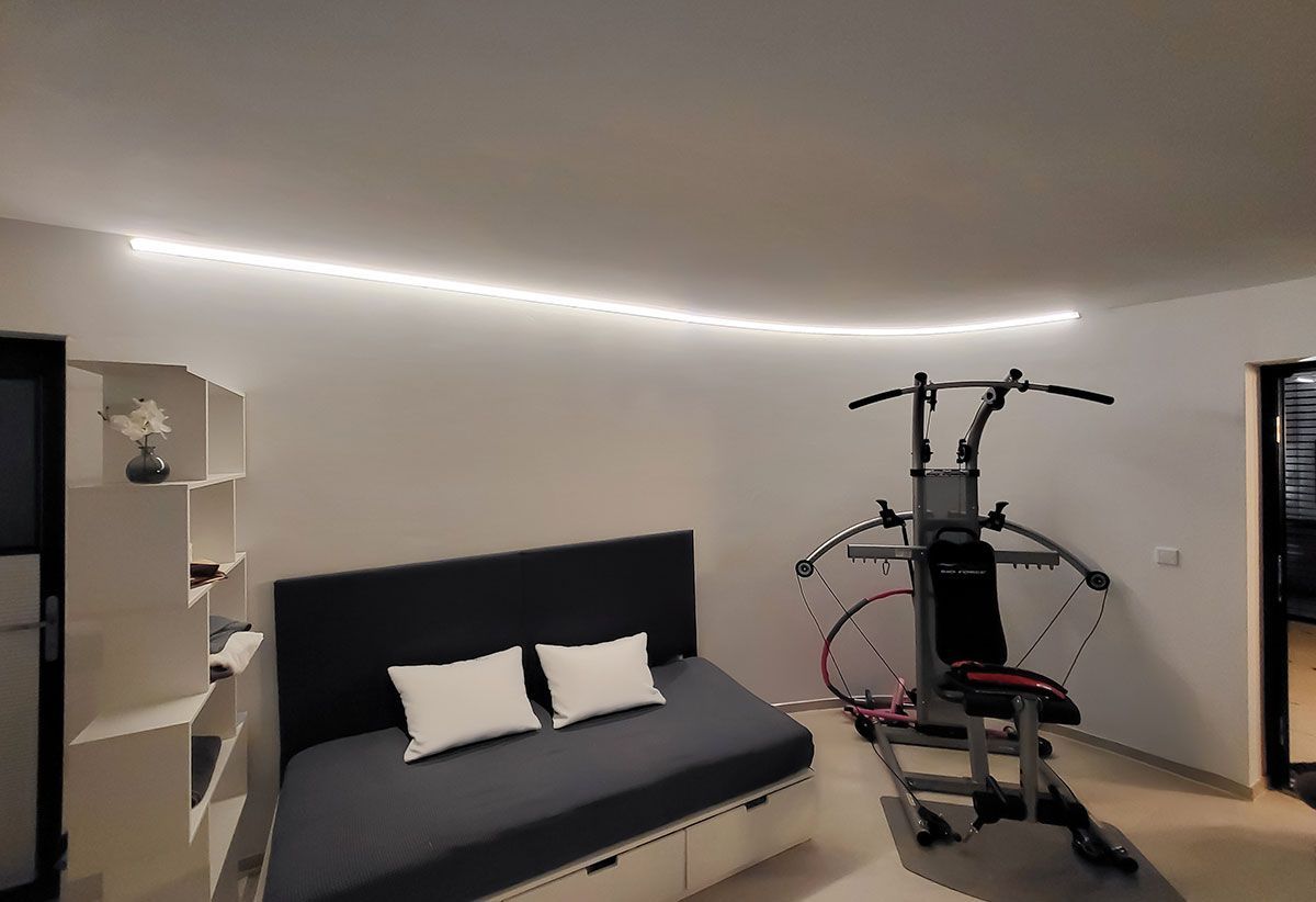 Projektbeispiel Lichtplanung: Modernes Wellnessraum mit einer gebogenen LED-Stripe-Beleuchtung als Blickfang an der Wand