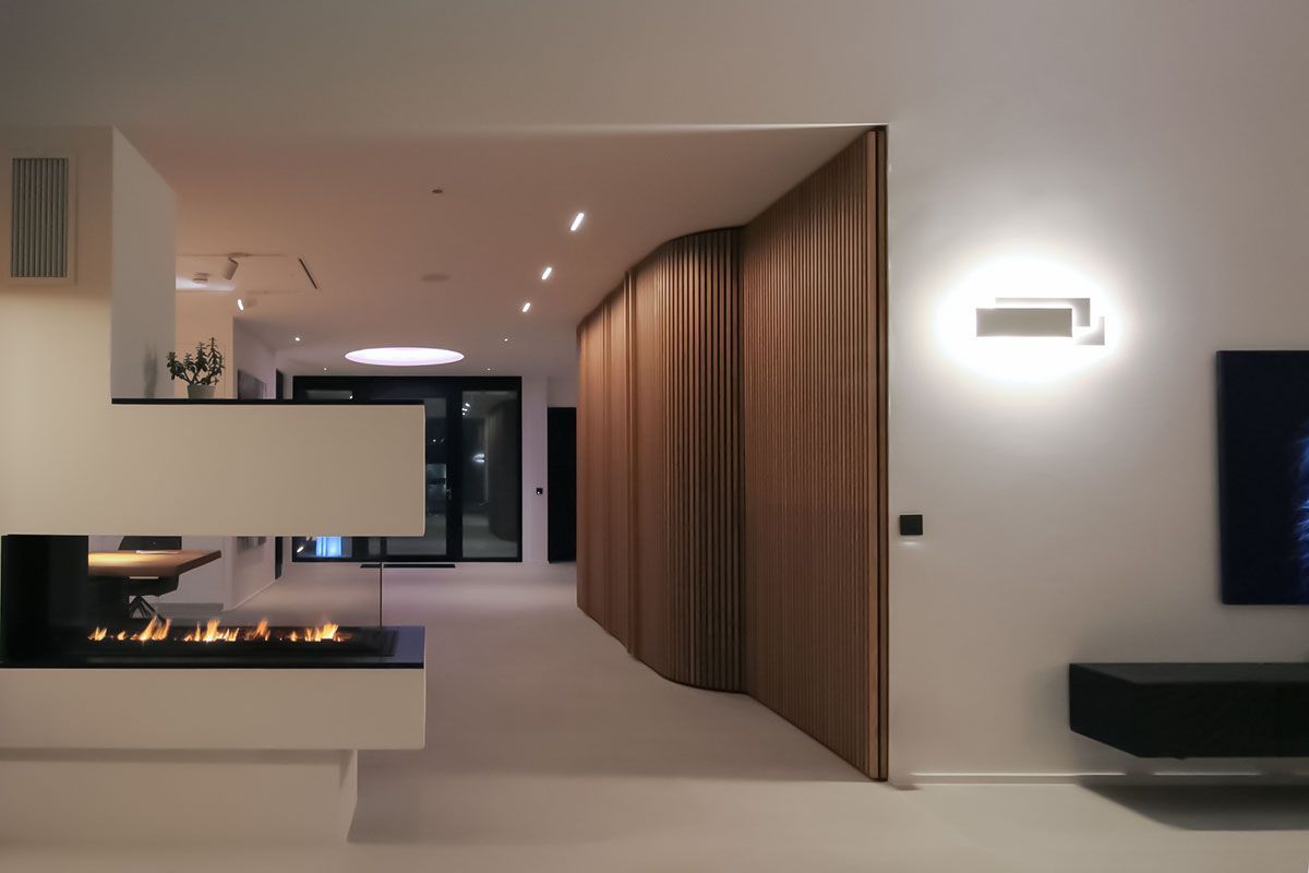 Innenraum-Lichtplanung: Geometrische Wandleuchte, Decken-Einbaustrahler und indirektes Licht an Holzlamellenwand.