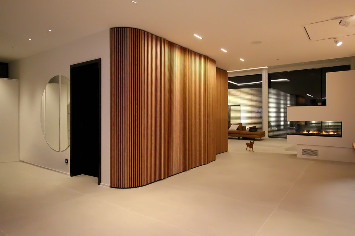 Zonierte Wohnraumbeleuchtung: Bündige LED-Lichtlinien an der Decke akzentuieren den Flur und die Holzlamellenwand.