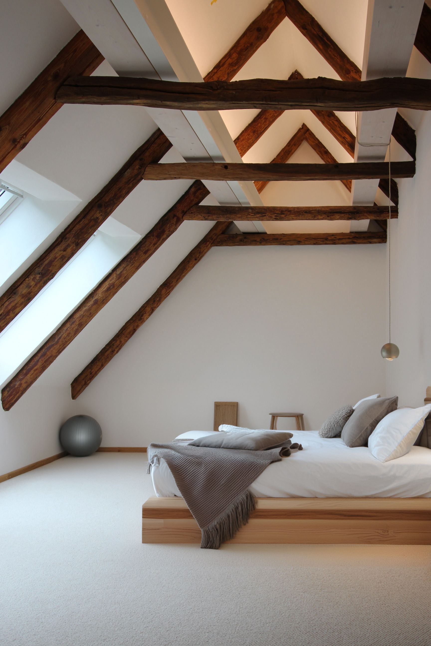 Schlafzimmer-Beleuchtung: Indirektes Licht über rustikalen Deckenbalken und tief hängende Spider-Leseleuchte am Bett.