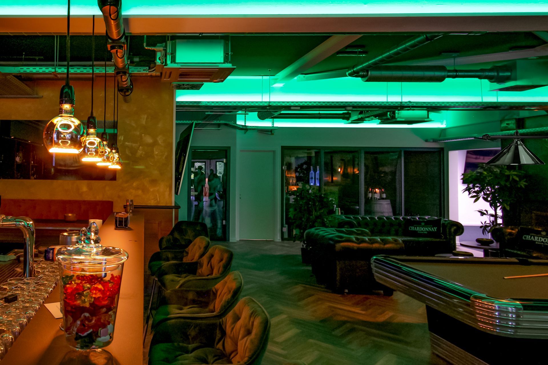 Gastronomie-Lichtkonzept: Grüne LED-Deckenbänder, warme Pendelleuchten über dem Tresen und beleuchteter Billardtisch.