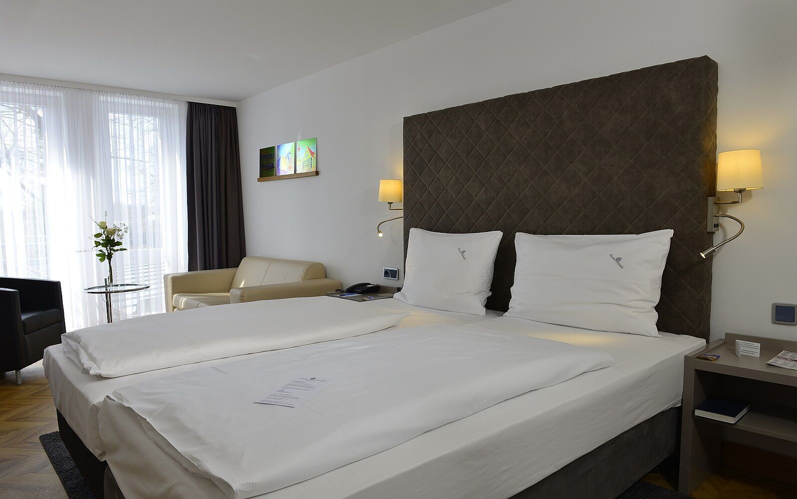 Hotelzimmer-Beleuchtung: Zwei Nachttischlampen mit integrierten Schwanenhals-Leselampen flankieren das Doppelbett.