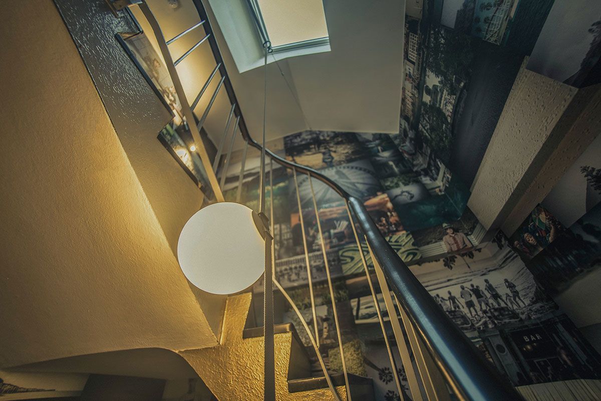 Warmes Licht einer Design-Pendelleuchte erhellt die Stufen und Wände im Treppenhaus.