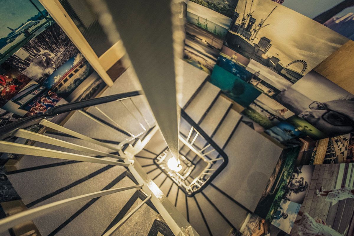 Zentrale Kugelleuchte im Treppenhaus sorgt für warme Beleuchtung der gestalteten Fotowand.