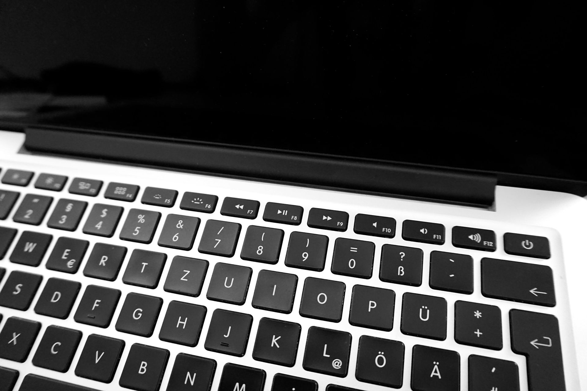 Close-up of a silver laptop with a black keyboard, including QWERTZ layout keys and a black display screen.