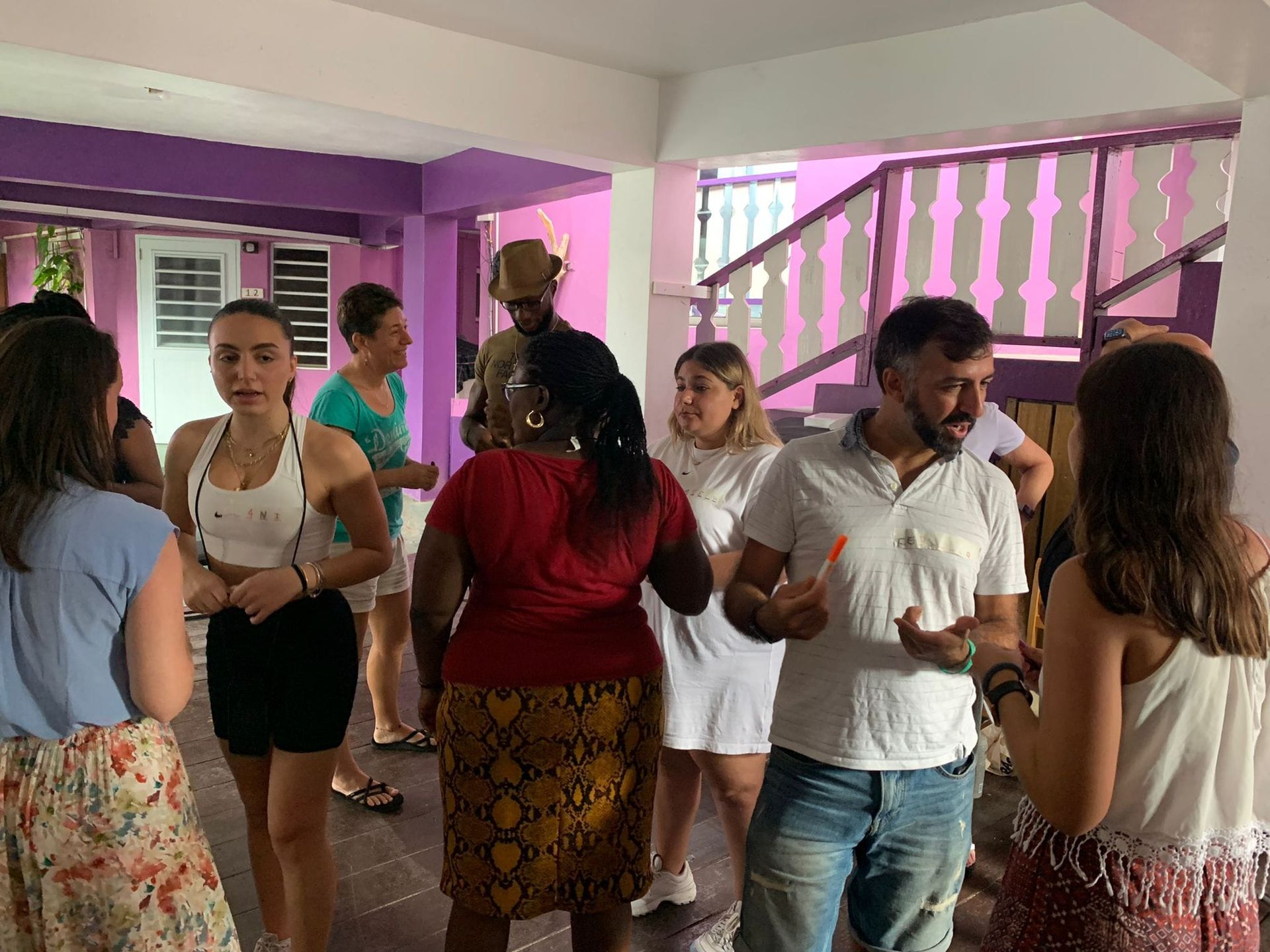 People in an interior space, some conversing. Purple and white walls.