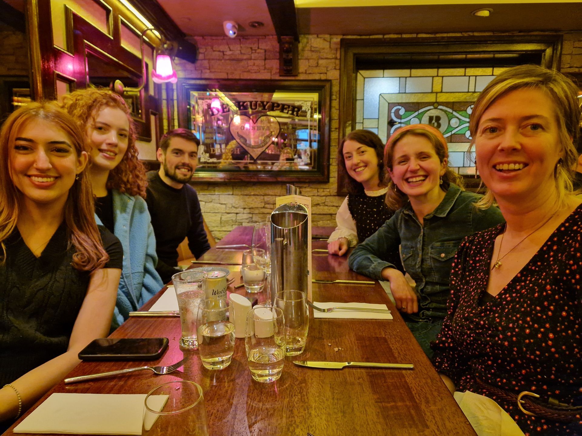 Group of six people seated around a table at a restaurant, smiling at the camera.