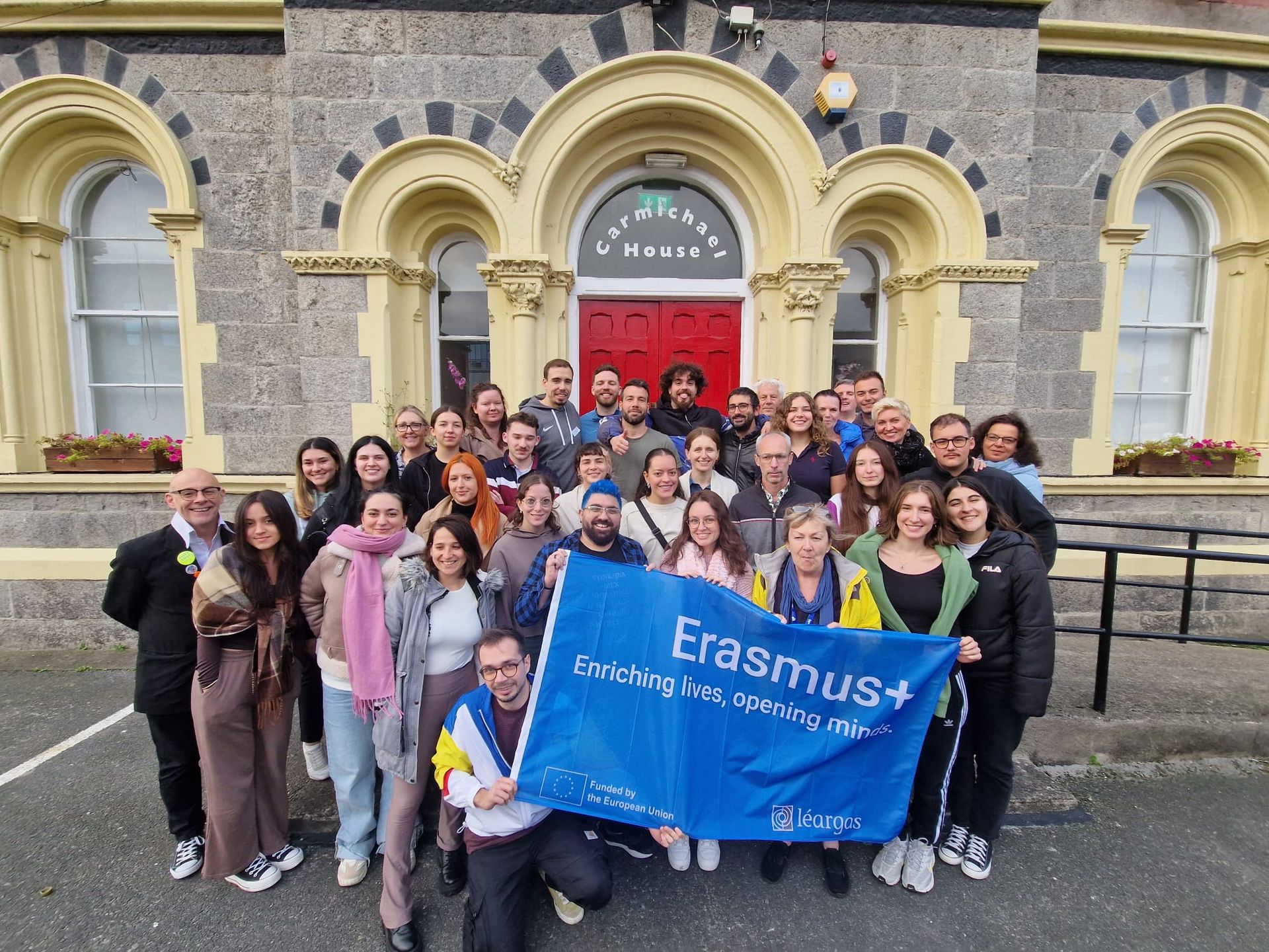 Group poses in front of a building with banner reading 