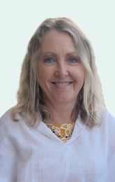 Woman with blonde wavy hair smiles at the camera, wearing a white shirt with yellow lace collar.