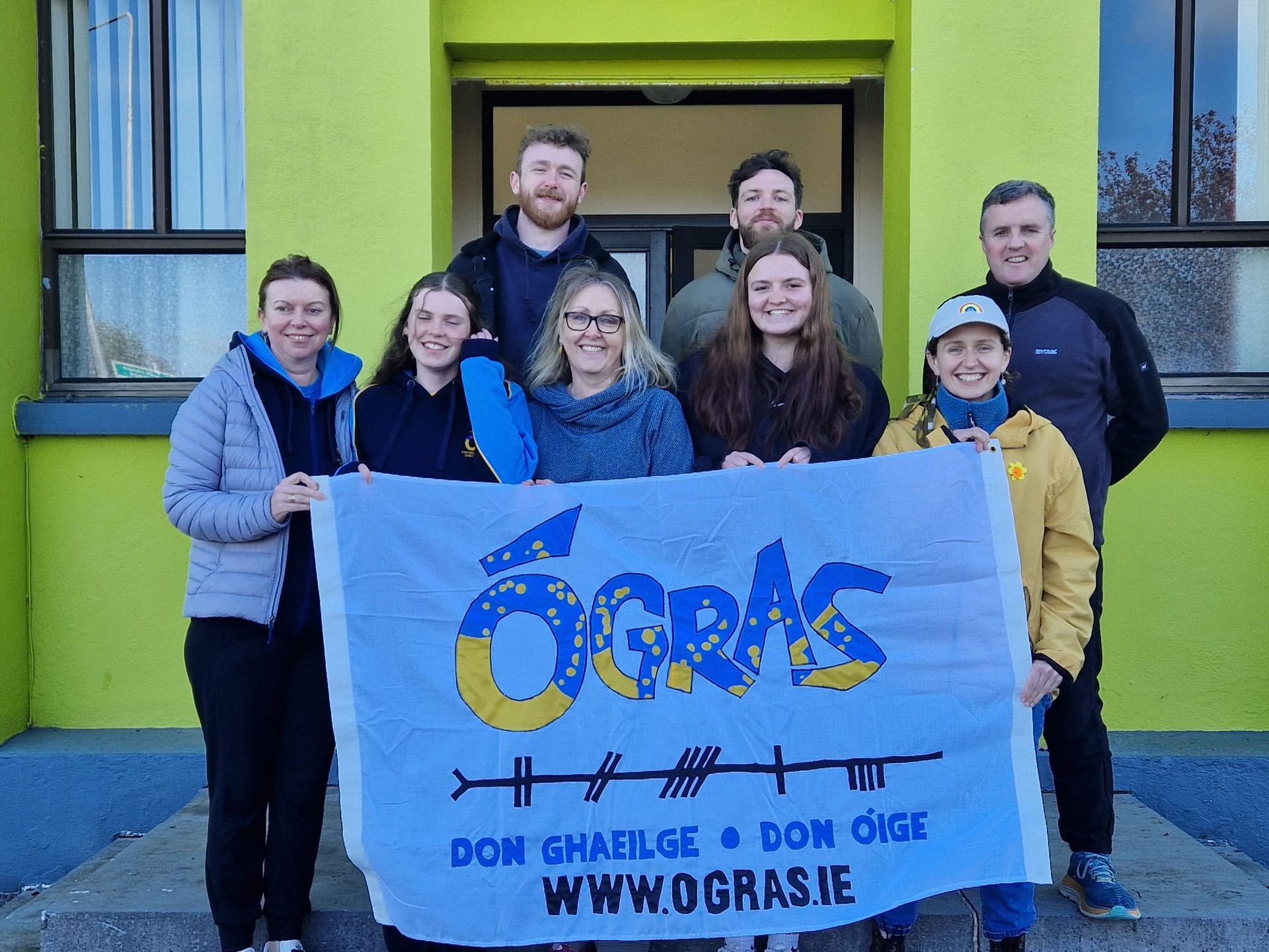 Group holding a blue and yellow flag that reads
