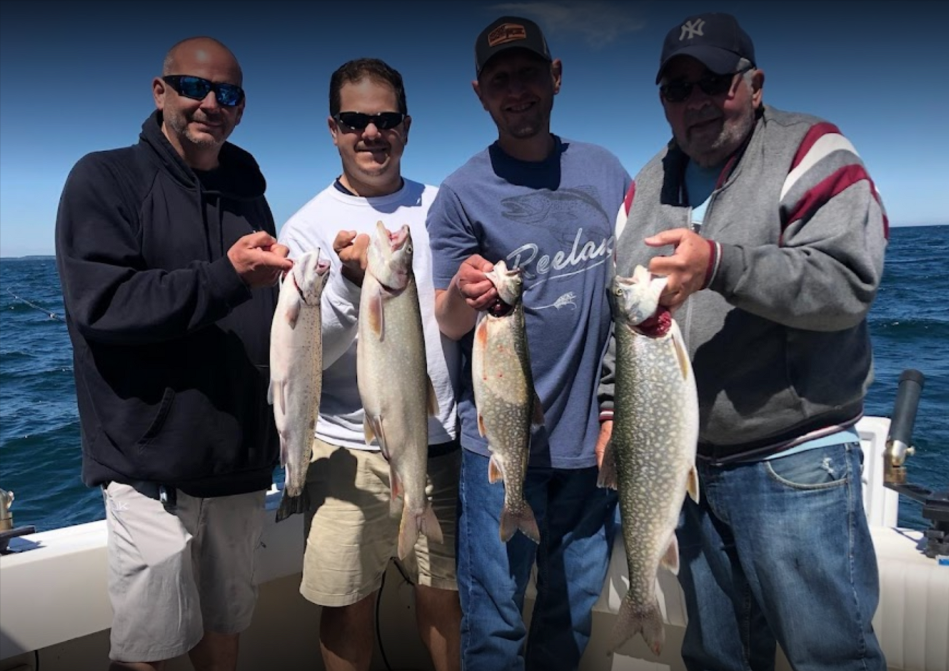 A group of men are standing on a boat holding fish.