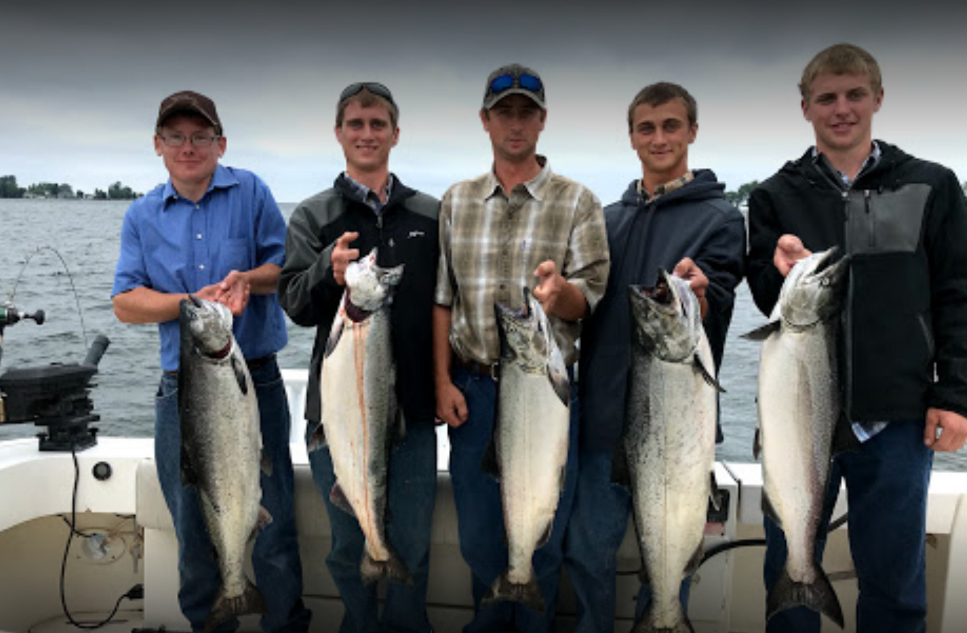A group of men are standing on a boat holding fish.