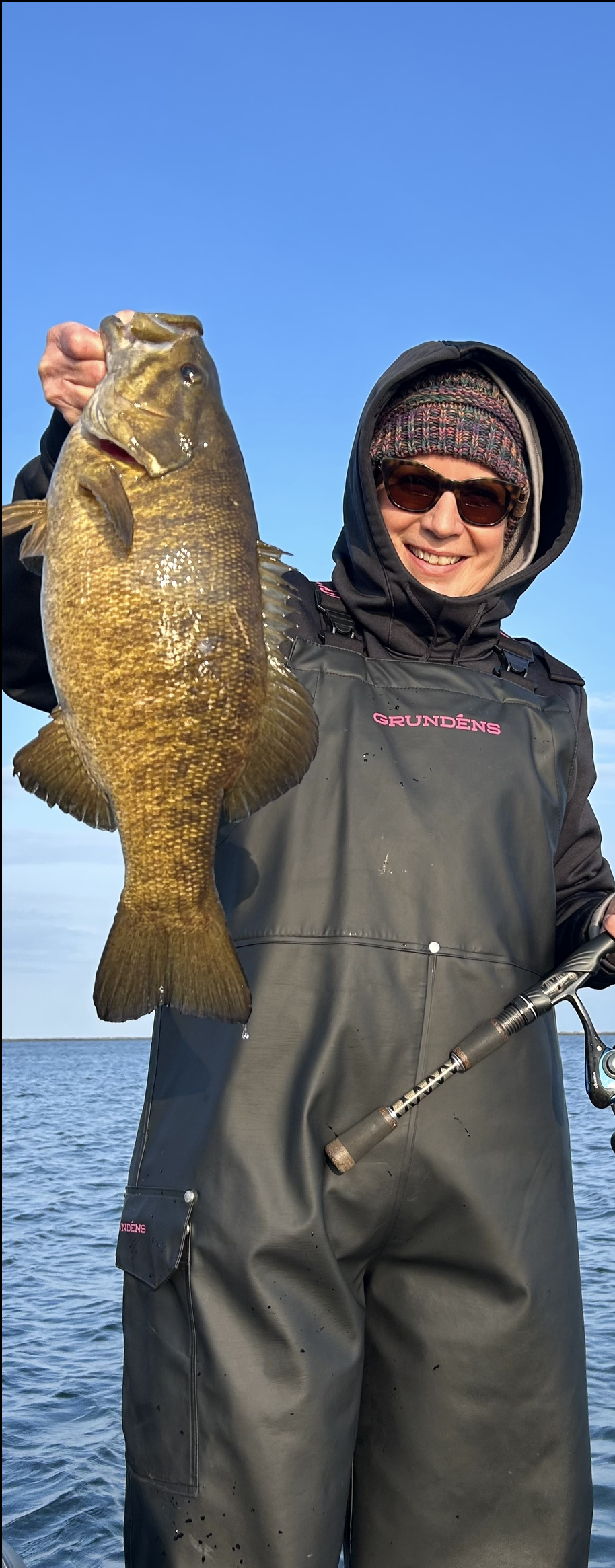 A woman is holding a large fish in her hands in the water.