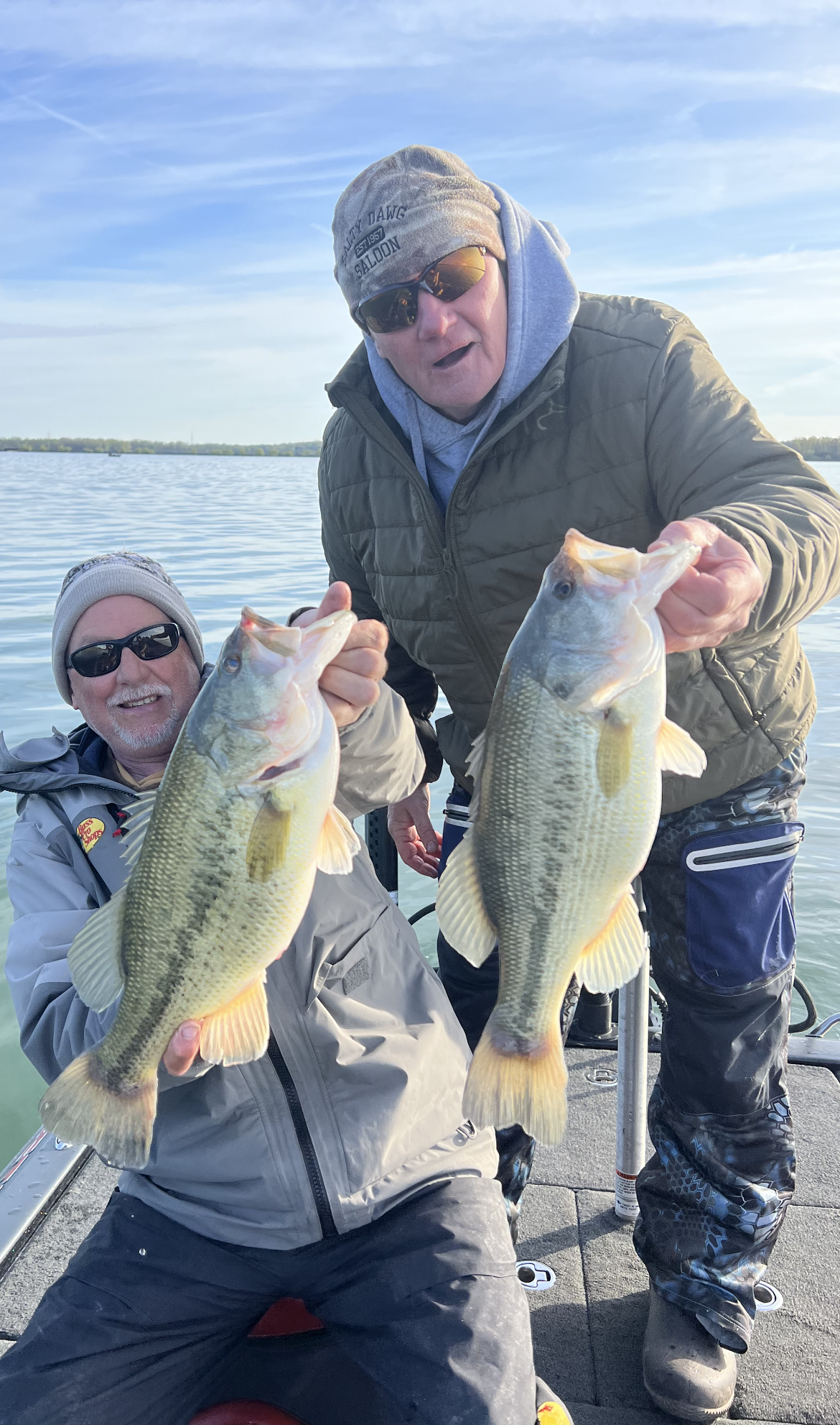 Two men on a dock holding Bass they just caught