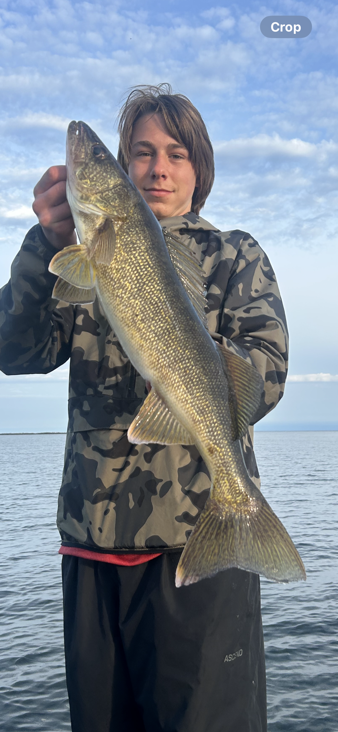 A young man is holding a large Salmon fish in his hands.