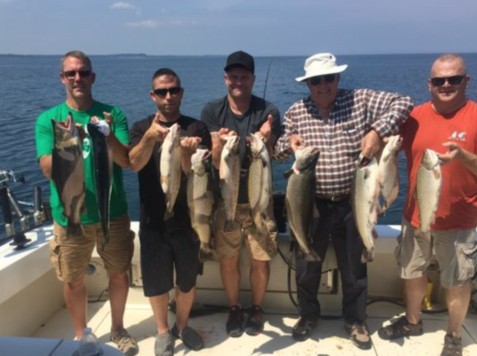 A group of men are standing on a boat holding fish.