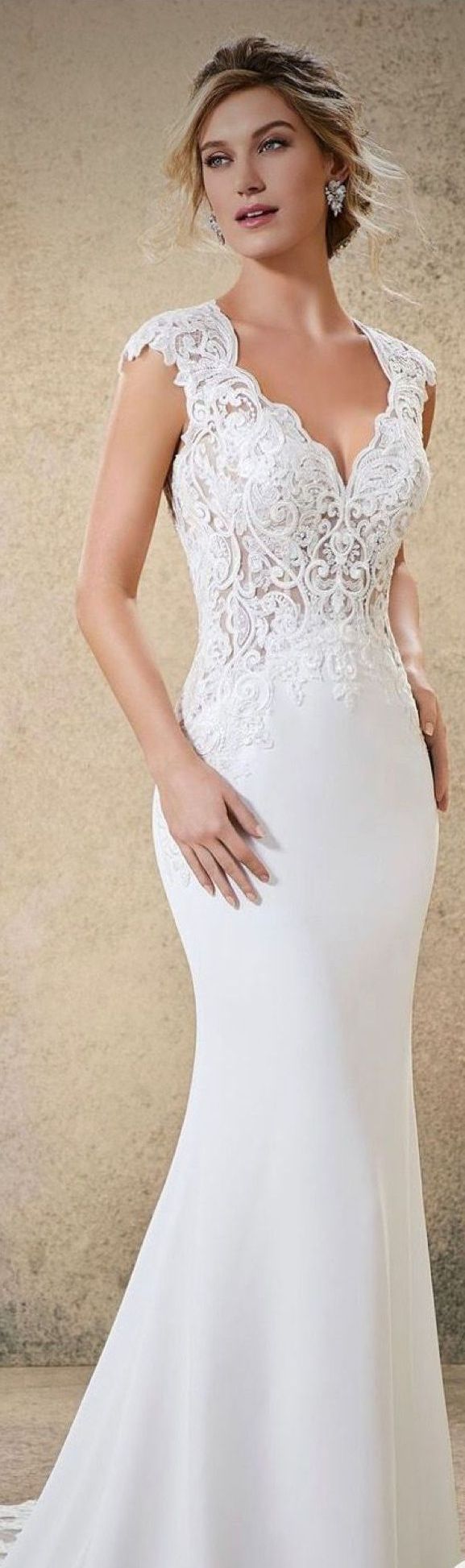 Woman wearing a white wedding dress with lace bodice, posing in a studio.