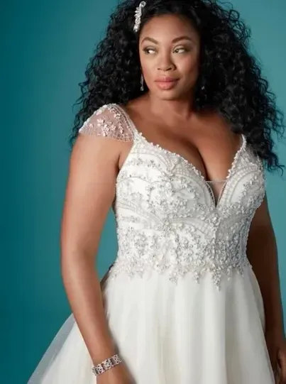 Woman in a white wedding dress with beaded bodice, against a teal background.