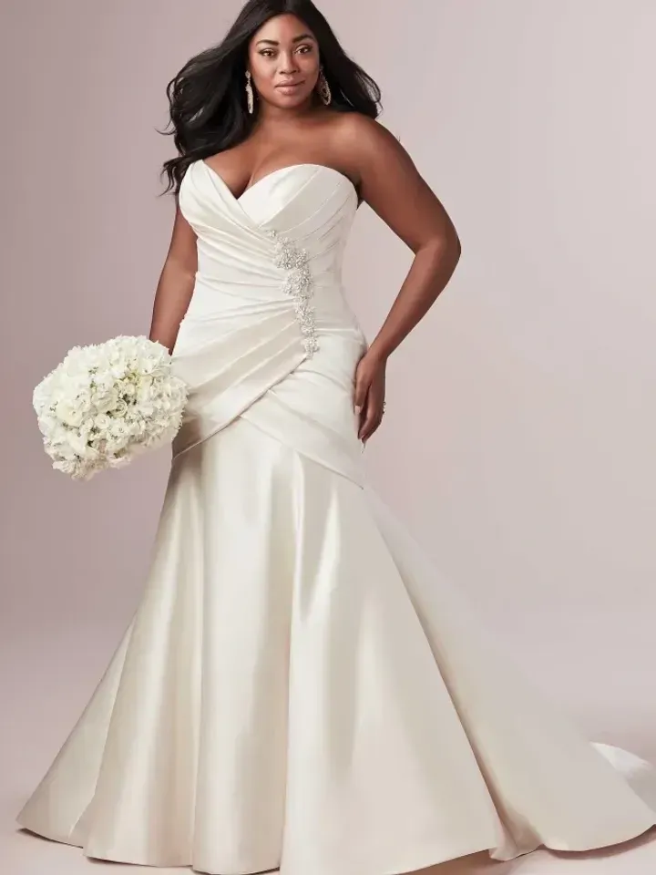 Woman in a strapless ivory wedding dress, holding a white bouquet.