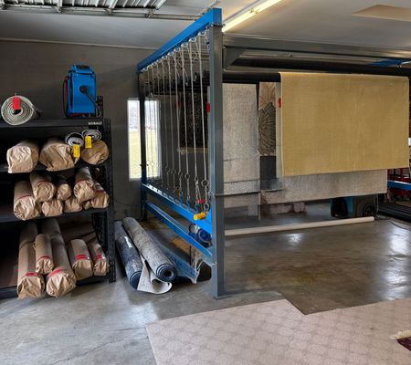 Robert's Cleaning and Restoration - A room with a lot of carpets hanging on a rack