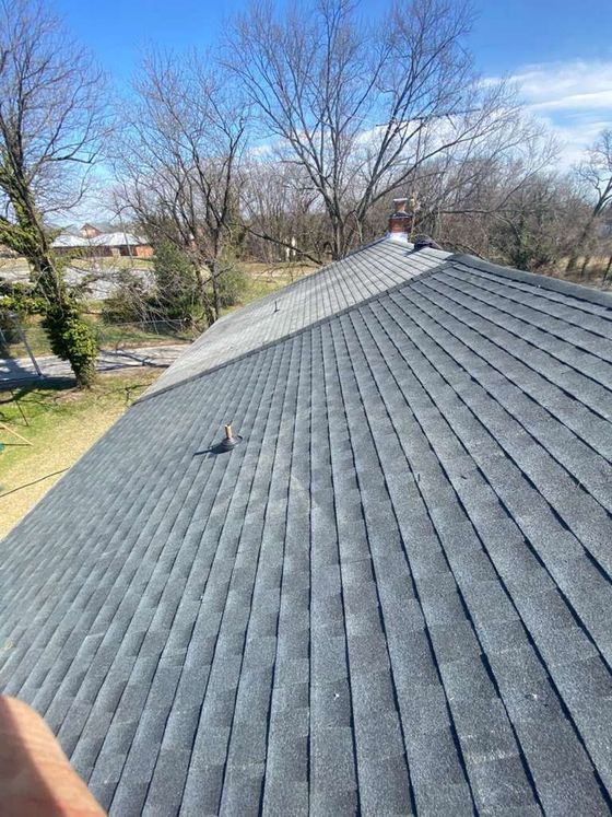 Worker installing blue roof tiles on a house under a sunny sky