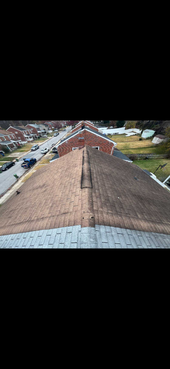 Worker installing metal roofing on a rooftop under a bright sky.