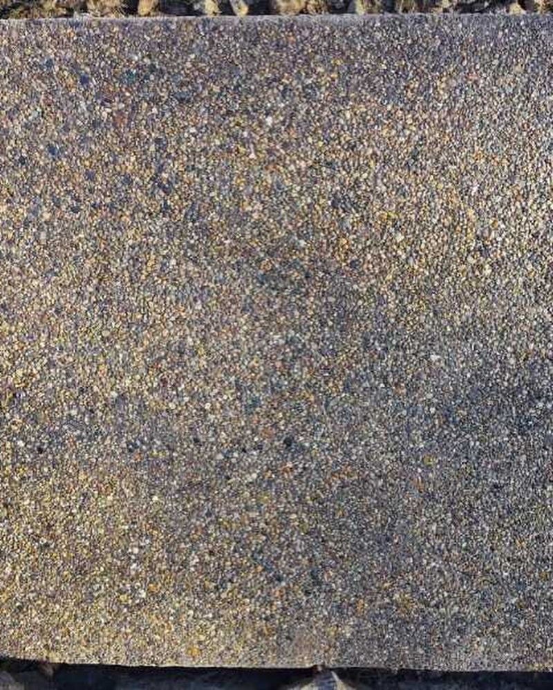 Close-up of a rectangular concrete paver with a textured, speckled surface in shades of gray and tan.
