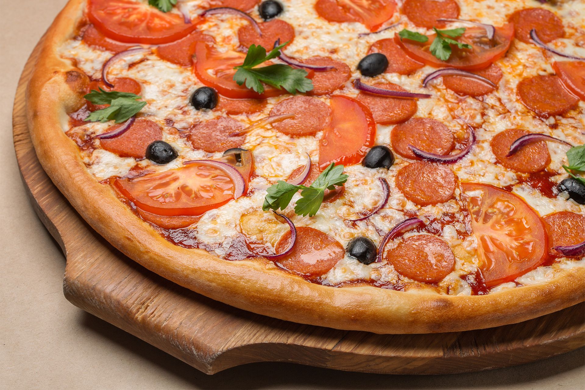 Pepperoni and olive pizza on a wooden board, topped with tomatoes and basil. Pepperoni and olive pizza on a wooden board, topped with tomatoes and basil.