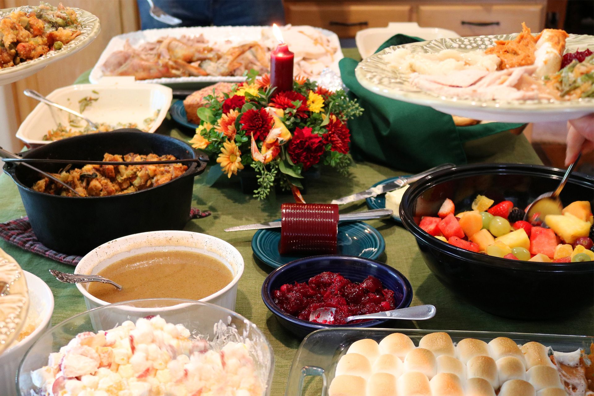 A holiday buffet table with assorted dishes, fruit, and a floral centerpiece. A holiday buffet table with assorted dishes, fruit, and a floral centerpiece.
