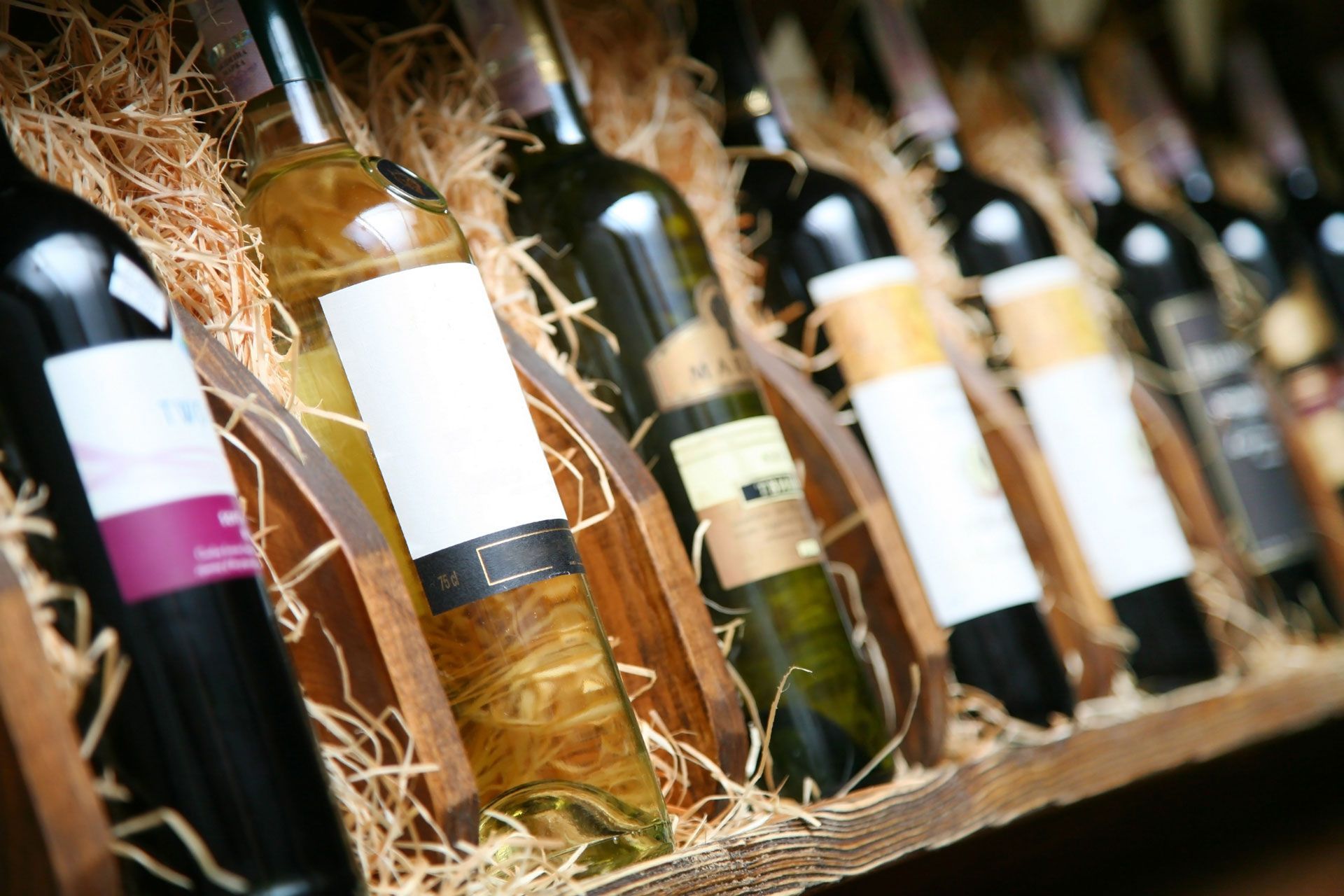 Wine bottles lined up in a rack with straw filler, viewed at an angle